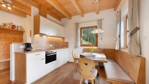 Interior de madera con cocina, comedor y ventana con cortinas.