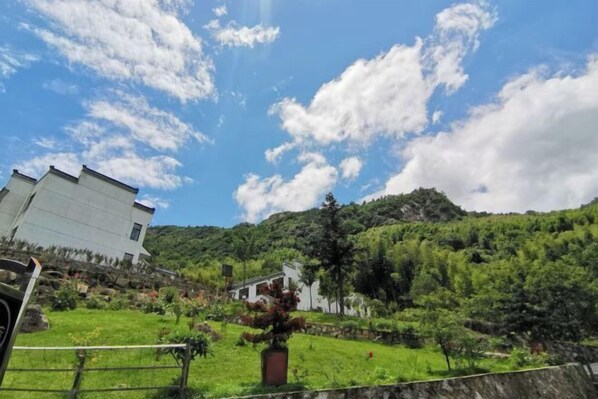 Un cerro con un edificio blanco, exuberante vegetación y un cielo azul despejado.