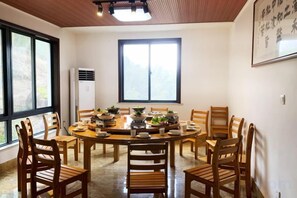 Un coin repas avec une table ronde, des chaises et une grande fenêtre.