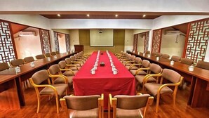 A conference room with a long table, multiple chairs, and a projector screen. - Tiantang Mountain Original Ecological Resort (Guangde)