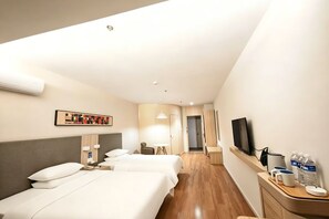 A hotel room with two beds, a desk, a TV, and a bathroom in the background. - Hanting Hotel (Wuxi Qianzhou Wuzhou International Plaza) (Wuxi)