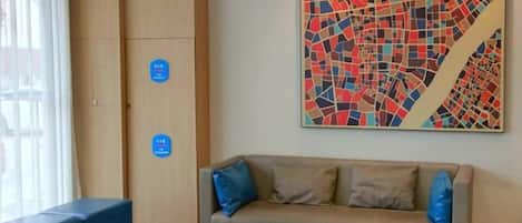 A room with a sofa, a round wooden table, and a colorful abstract painting on the wall.