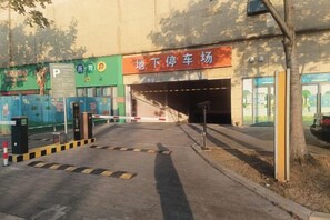 A parking entrance with a sign, a gated area, and a building entrance. - Hanting Hotel (Wuxi Qianzhou Wuzhou International Plaza) (Wuxi)