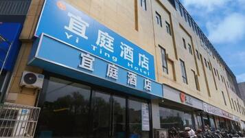 A hotel with a prominent blue sign, large windows, and a row of parked motorcycles outside.