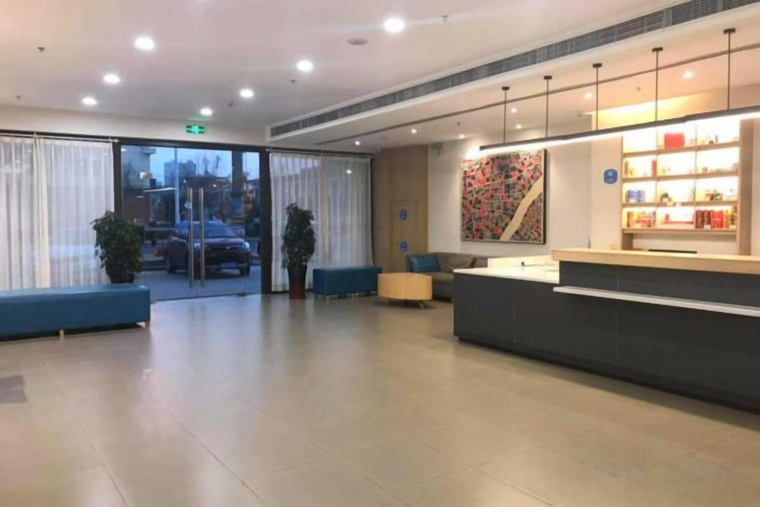 A hotel reception area with a counter, seating, and a view through the glass doors.