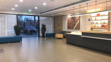 A hotel reception area with a counter, seating, and a view through the glass doors.