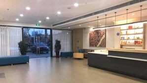 A modern reception area with a reception desk, seating, and a large window. - Hanting Hotel (Wuxi Qianzhou Wuzhou International Plaza) (Wuxi)