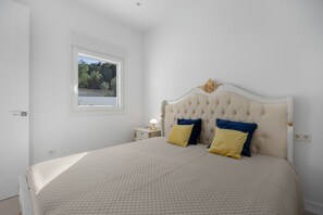 A bedroom with a bed, a nightstand, a window, and a door.
