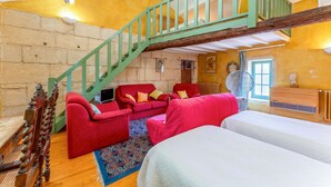 Ein Zimmer mit einer Holztreppe, roten Sofas, einem Bett und einer Steinwand.