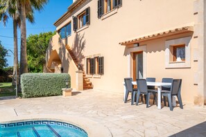 Une villa dotée d’une piscine, d’un espace salon extérieur et d’un escalier menant à l’étage supérieur.