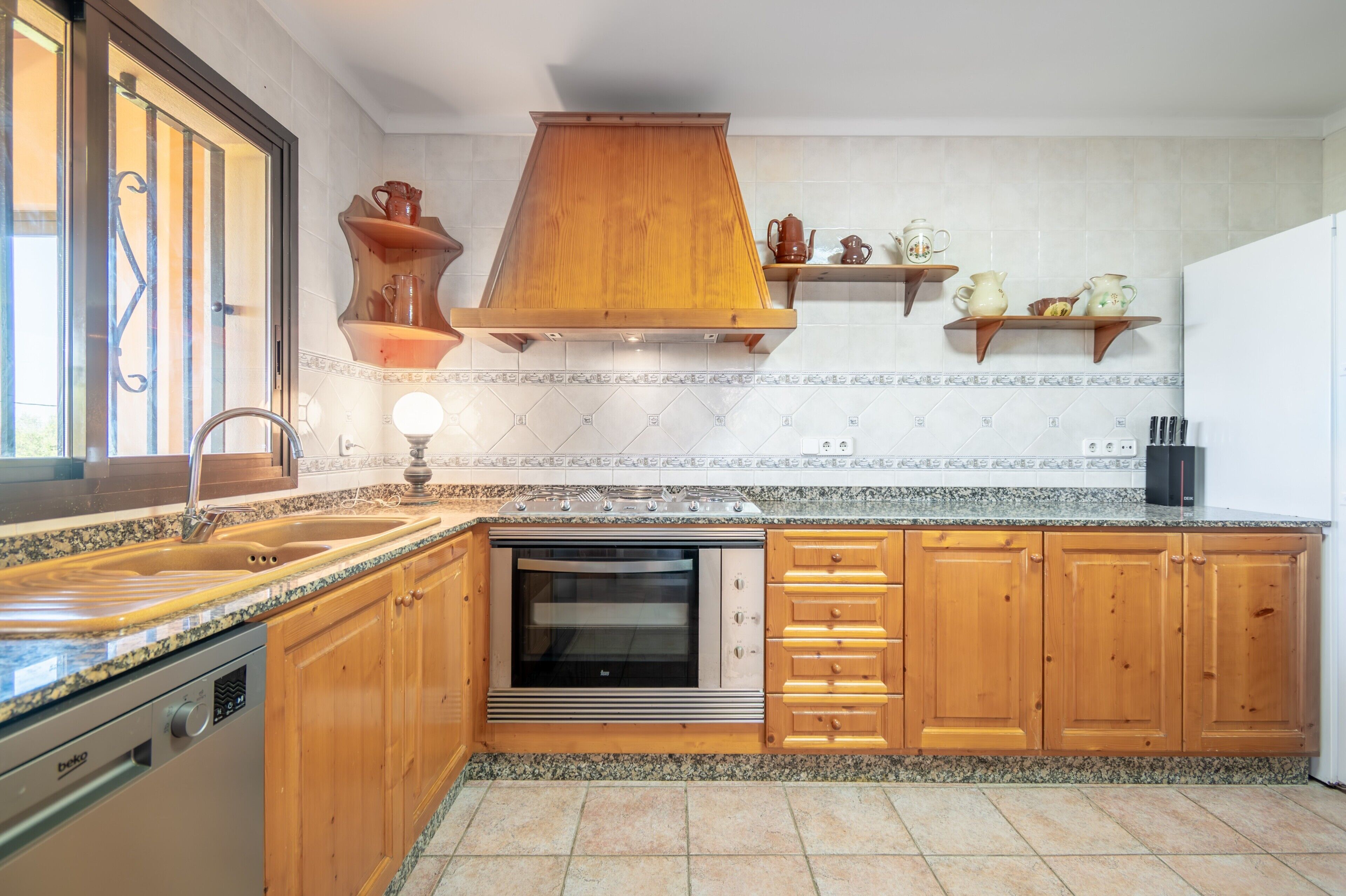 A kitchen with wooden cabinets, a built-in oven, a sink, and a window.