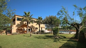 A two-story building with a swimming pool, surrounded by trees and a well-maintained lawn.