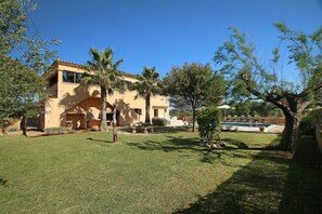 A two-story building with a swimming pool, surrounded by trees and a well-maintained lawn.