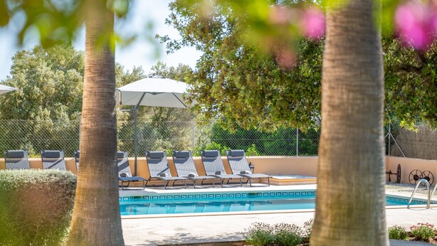 A pool area with lounge chairs and umbrellas.