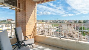Een balkon met uitzicht op een stadsgezicht, een bakstenen muur en twee stoelen.