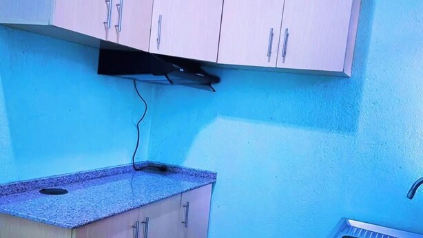 A small kitchen with light-colored cabinets, a countertop, and a sink. - La Lumiere De Madeleine (Gahengeri)
