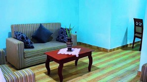 Un soggiorno con divani a righe, un tavolino in legno e una parete azzurra.