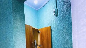 Una stanza piccola con pareti color verde acqua, un armadietto in legno, un tavolino con una teiera e una sedia con decorazioni elaborate.