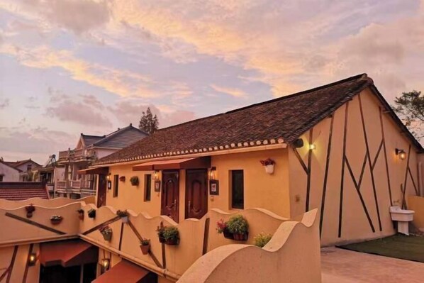 A building with a sloped roof, multiple windows, and outdoor lighting fixtures. - Shanghai Yuanlai Chinese Inn Cenbocun (Shanghai)