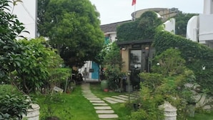 Un giardino con un vialetto in pietra, piante in vaso e un edificio con una porta in vetro.