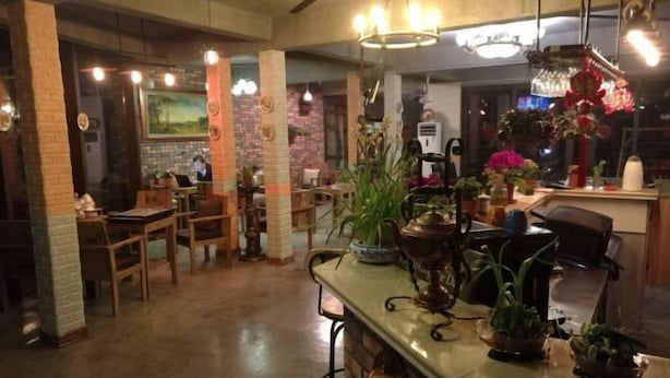 Un interno ristorante con pareti in mattoni, tavoli di legno, luci a sospensione e piante in vaso.