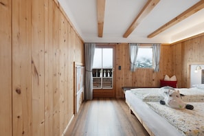 A wooden-paneled room with a bed, a window with curtains, and a view of the outdoors. - Room 'Rot' with Shared Terrace, Shared Garden and Wi-Fi (Villandro)