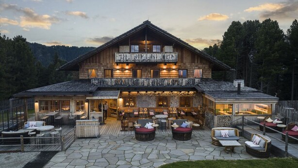 A large wooden building with a balcony, outdoor seating, and a stone patio. - Room 'Rot' with Shared Terrace, Shared Garden and Wi-Fi (Villandro)