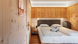 A wooden-paneled room with a bed, a nightstand, and a suitcase. - Room 'Orange' with Shared Terrace, Shared Garden and Wi-Fi (Villandro)