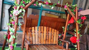 A rustic wooden swing chair with a natural design, surrounded by decorative vines and flowers. - Costa Resort（Xiachuan Island） (Taishan)