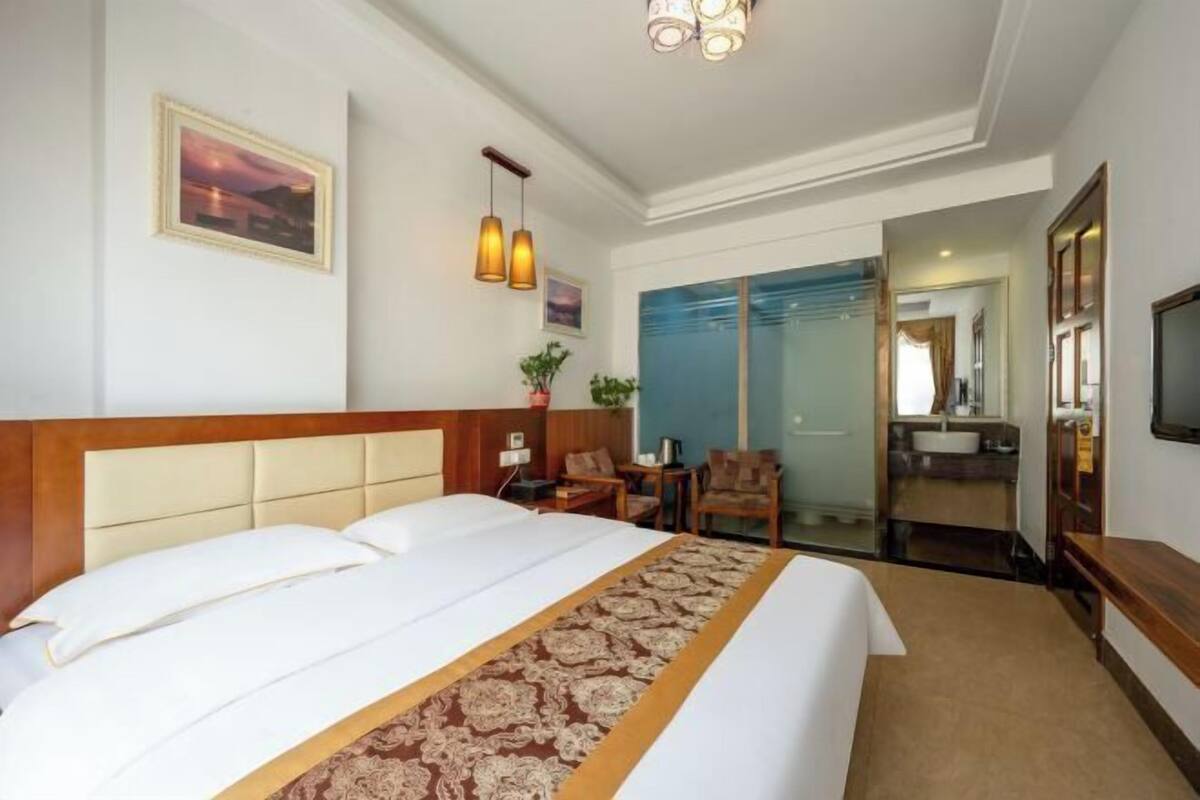 Hotelkamer met een groot bed, een bureau, een stoel, een televisie en een badkamer zichtbaar door een glazen deur.