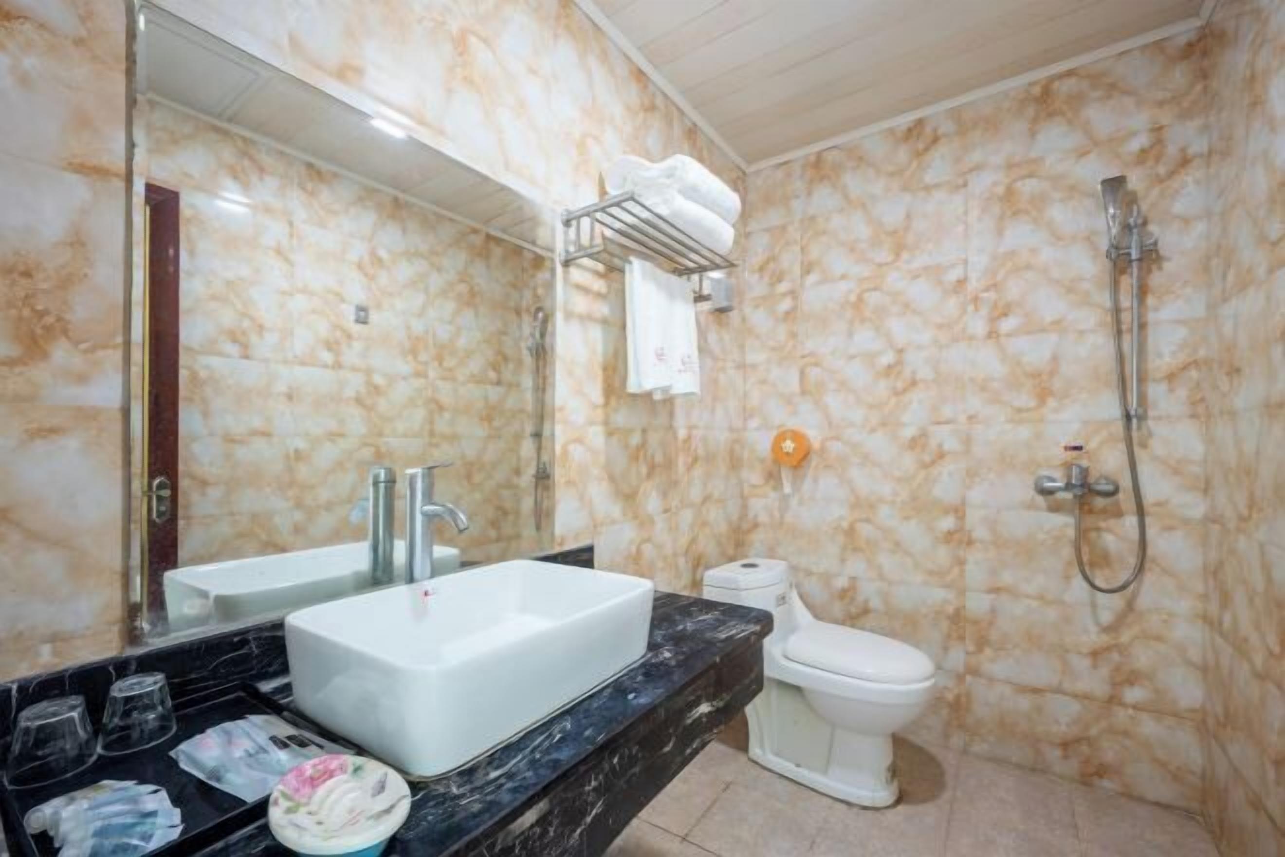 Un bagno con parete in marmo, lavandino bianco, WC e doccia.