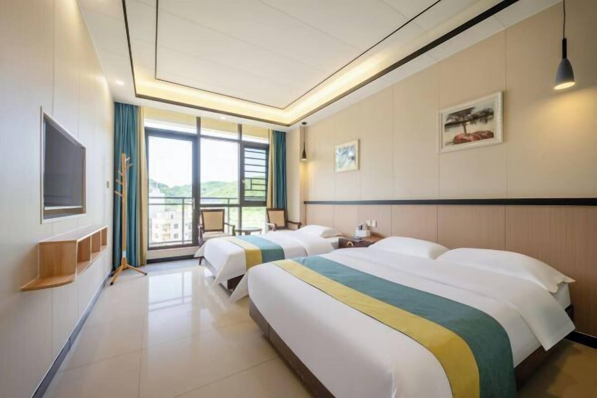 Een hotelkamer met twee bedden, een televisie, een bureau en een raam met uitzicht.