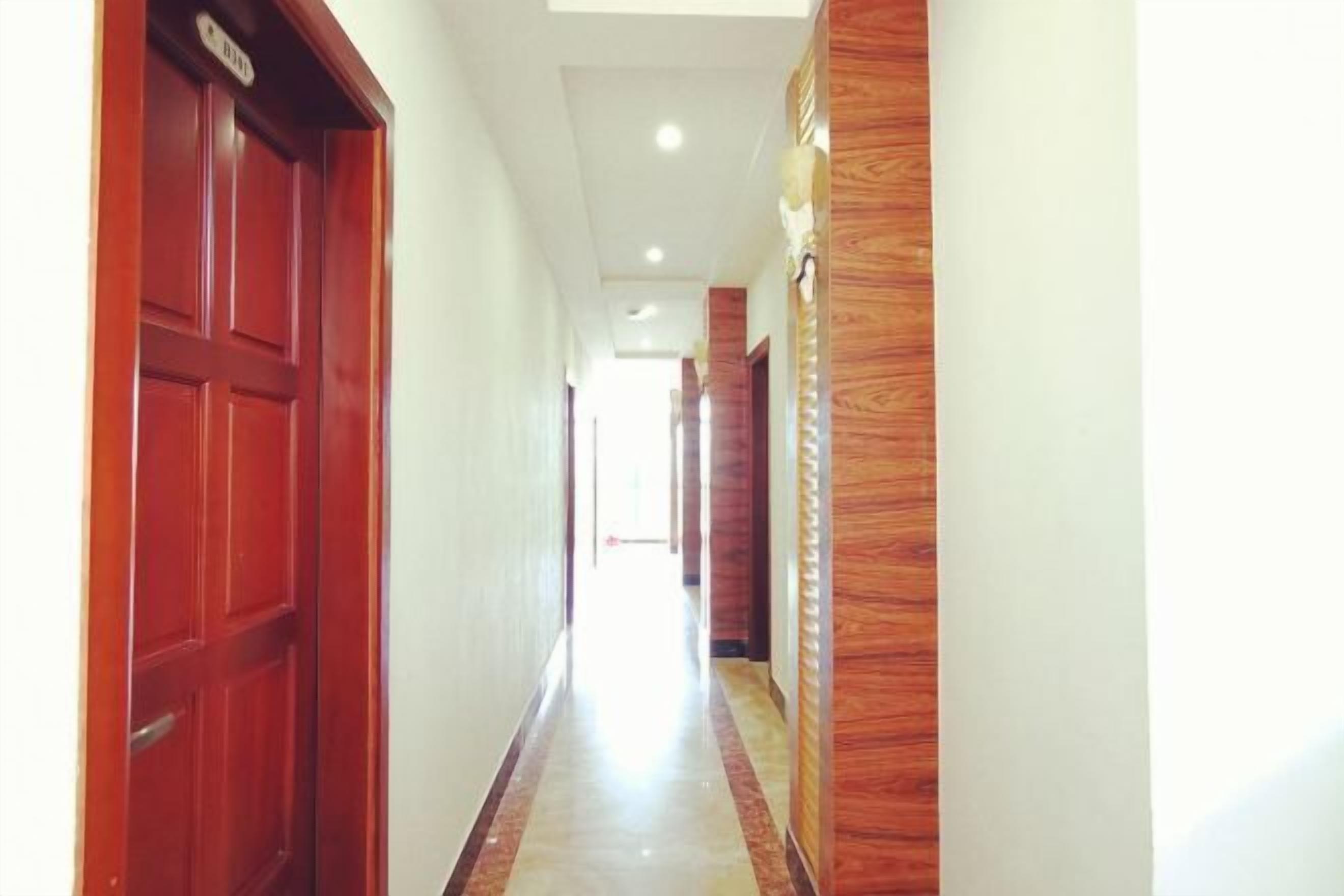 A hallway with a wooden door on the left and a wooden panel wall on the right.