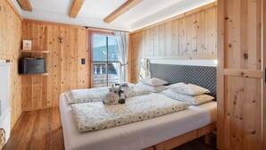 Een kamer met houten lambrisering, een bed en uitzicht op buiten.