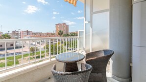 Un balcon agrémenté de meubles en osier, une vue sur le paysage urbain et un bâtiment en arrière-plan.