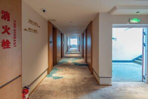 A hotel hallway with fire hydrant signs, a fire alarm, and a staircase leading to an outdoor area. - Huaying Hotel (Shaowu)