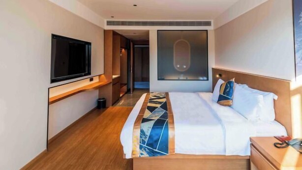Et moderne hotelværelse med en stor seng, et fladskærms-tv på væggen og et stort vindue.