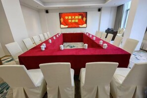 A conference room with a long table, white chairs, and a red tablecloth. - Huaying Hotel (Shaowu)