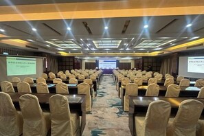 A conference room with rows of tables and chairs, a carpeted floor, and a presentation screen at the front. - Huaying Hotel (Shaowu)