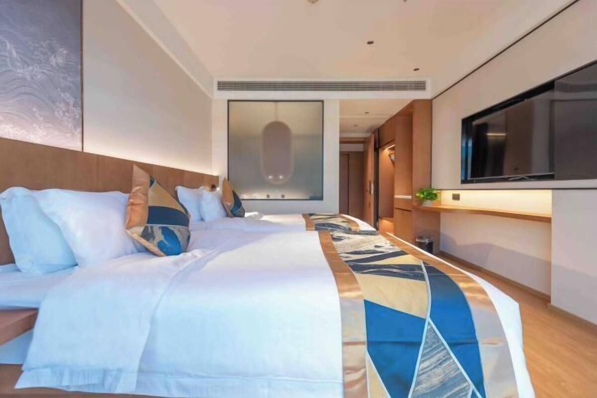 Une chambre d’hôtel moderne dotée d’un grand lit, d’une télévision à écran plat et offrant une vue sur la ville.