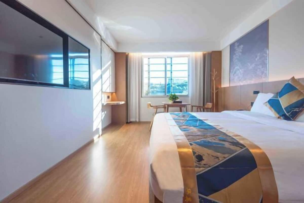Une chambre d’hôtel moderne, dotée d’un grand lit, d’un bureau et d’une fenêtre avec des rideaux.