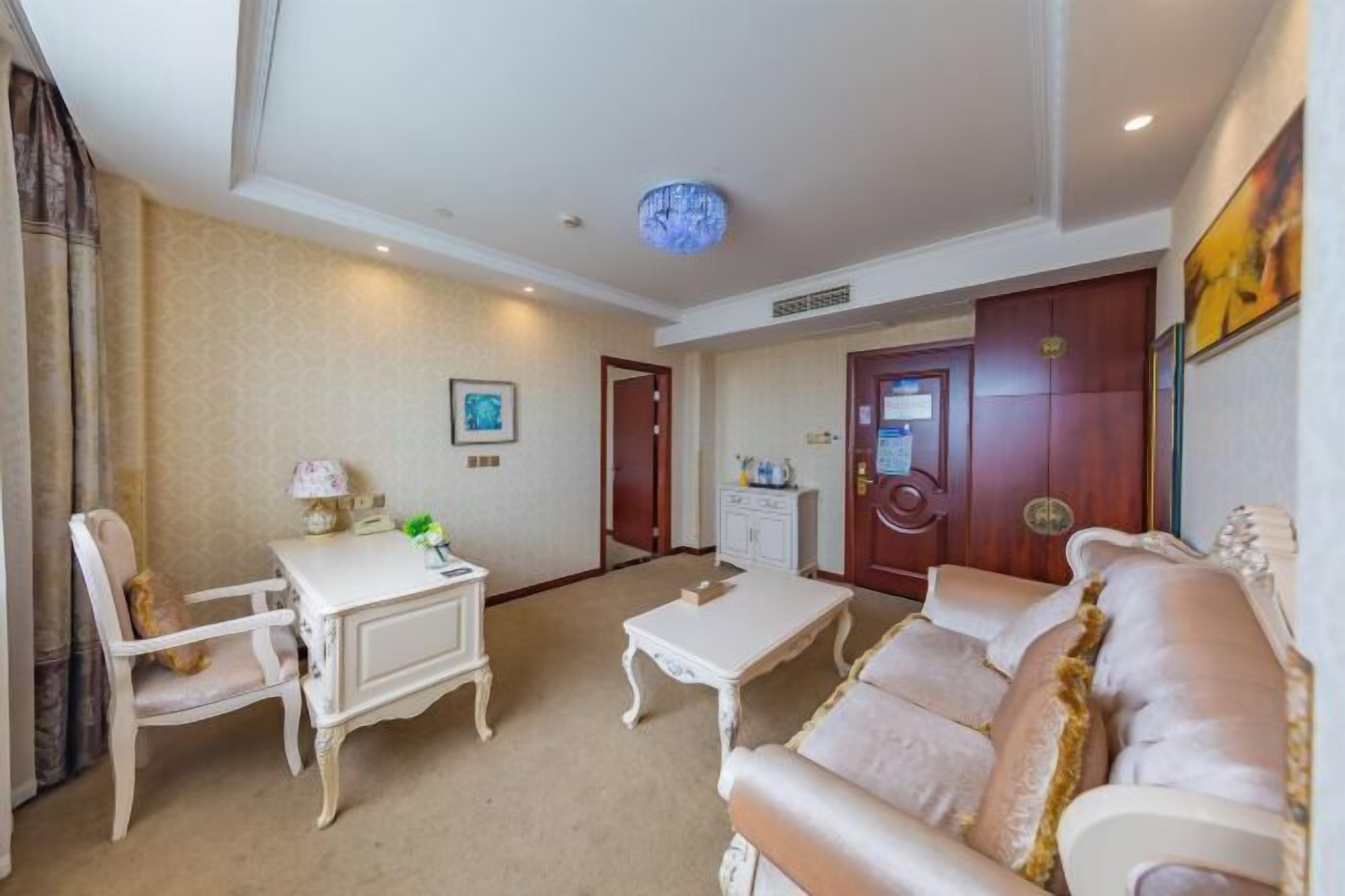 A room with a white sofa, a white table, a white armchair, and a wooden cabinet.