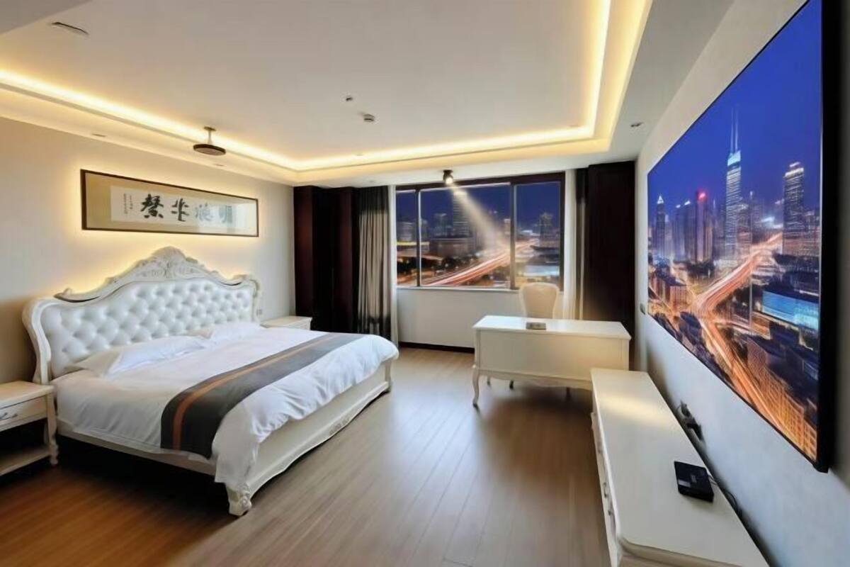 Una habitación de hotel moderna con una cama grande, un escritorio, una silla y un ventanal con vistas a la ciudad.