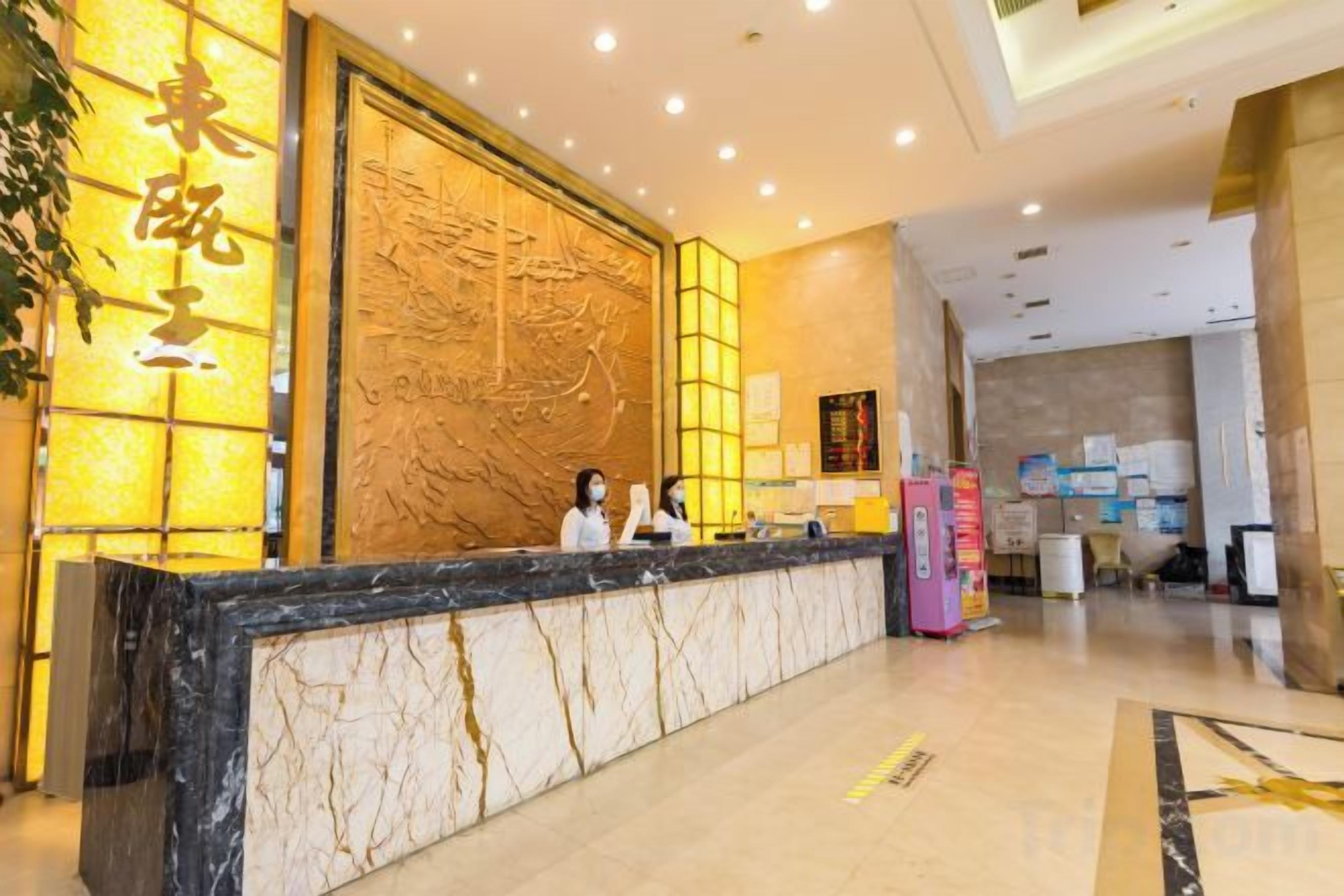 A hotel reception area with a marble reception desk, a large decorative wall, and a clean, modern interior.