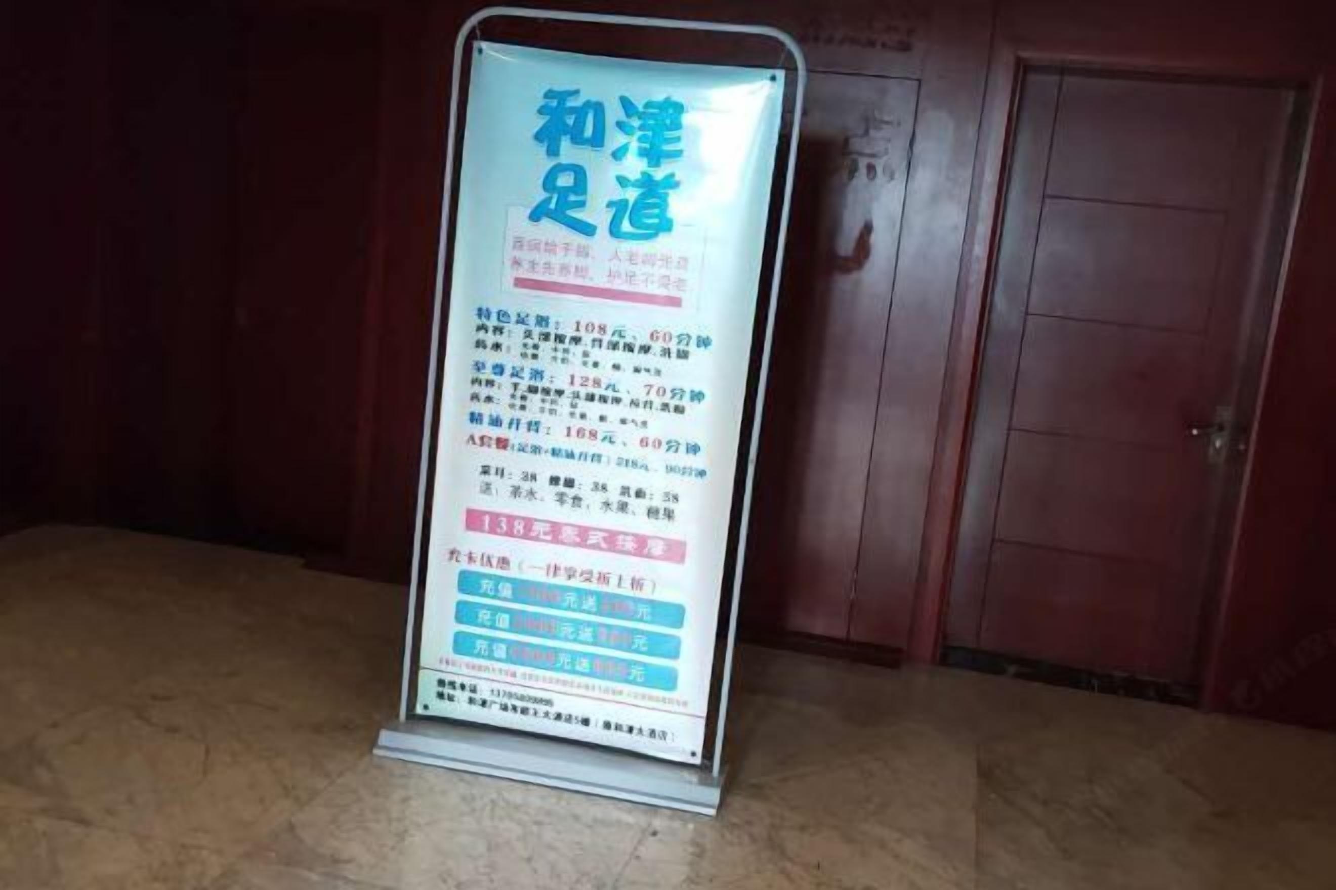 A vertical sign with text and prices in a foreign language, placed against a wooden background.