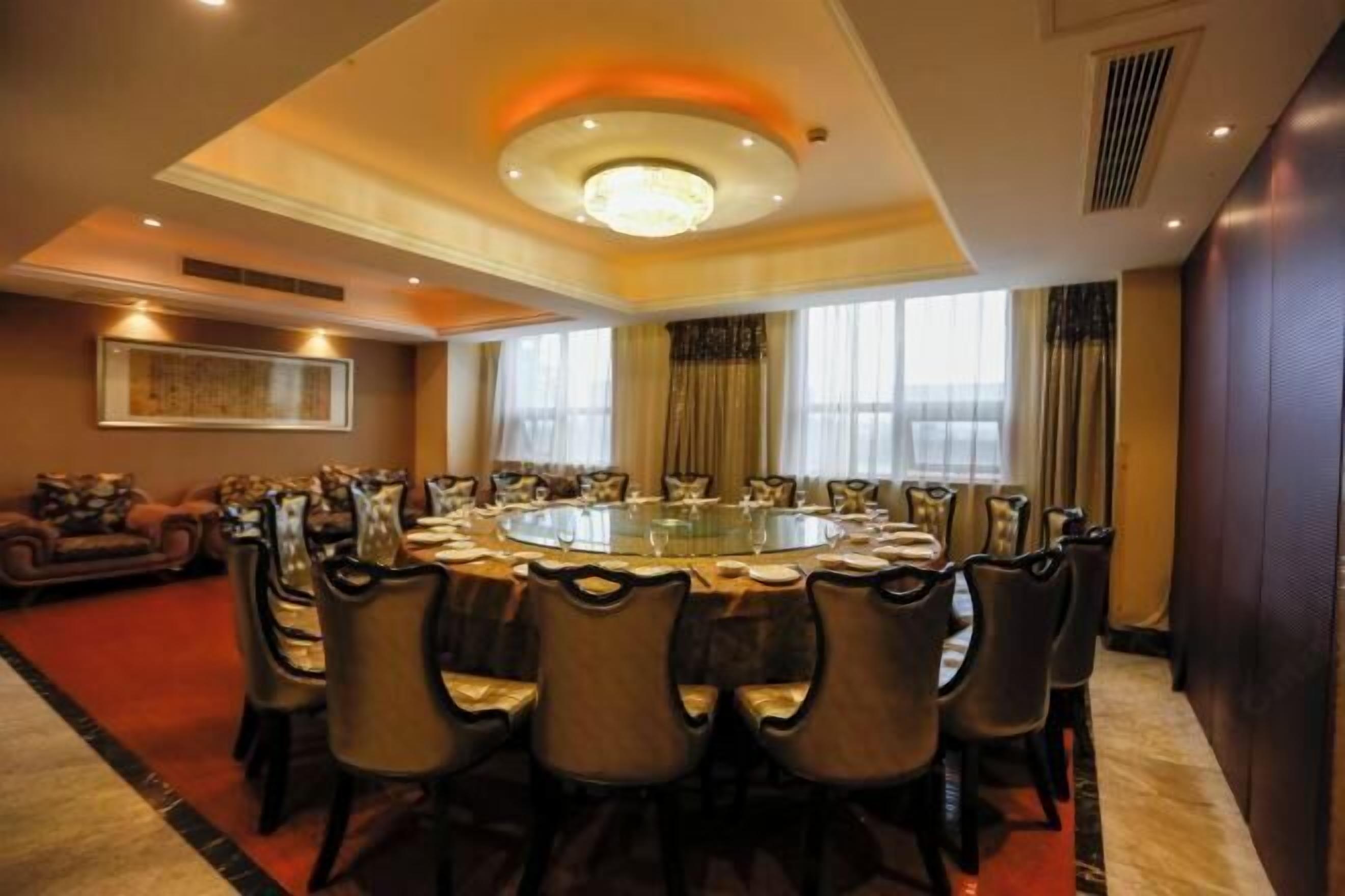A conference room with a round table, chairs, and a chandelier.