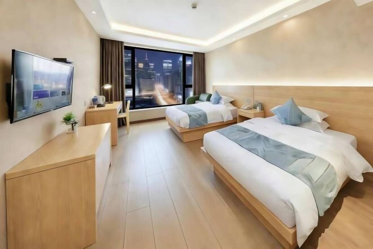 Habitación de hotel moderna con una cama grande, un escritorio, un televisor y vistas a la ciudad.