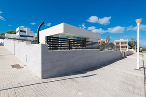A modern building with a flat roof, large windows, and a metal fence. - Holiday Home 'Es Mollet' with Sea Views, Private Pool and Wi-Fi (Son Serra de Marina)
