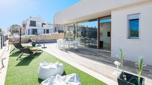 Une terrasse extérieure moderne, dotée d’un espace salon, d’une piscine et d’un coin repas fermé par des parois de verre.