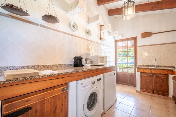 A kitchen with a washing machine, wooden cabinets, and a tiled backsplash.